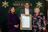 State Senator Melissa Hurtado, Assemblyman Rudy Salas, and Gina Sharra pose with a proclamation designating Allen Sharra Memorial Highway.